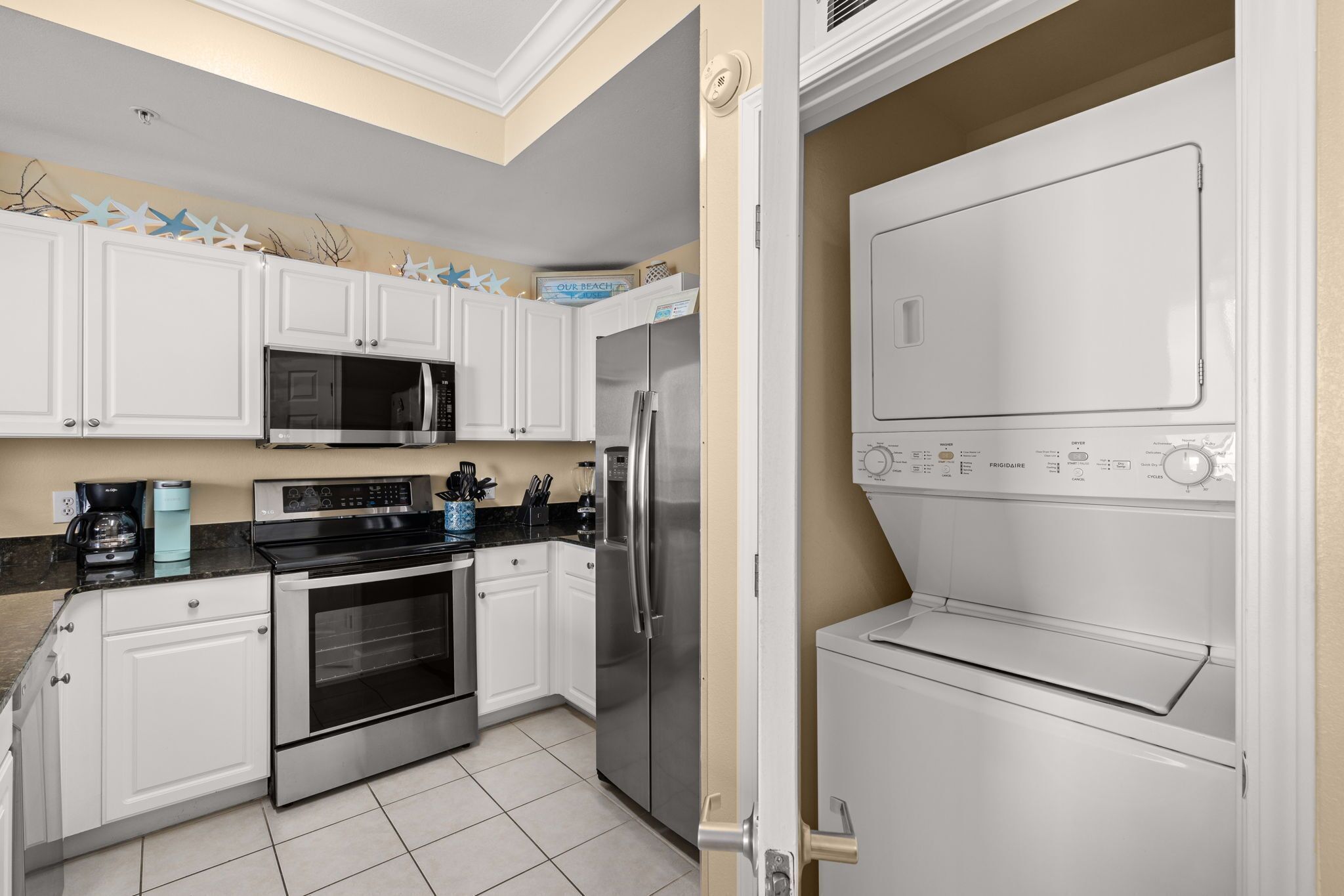 A modern kitchen with white cabinets, stainless steel appliances, and a built-in oven.
