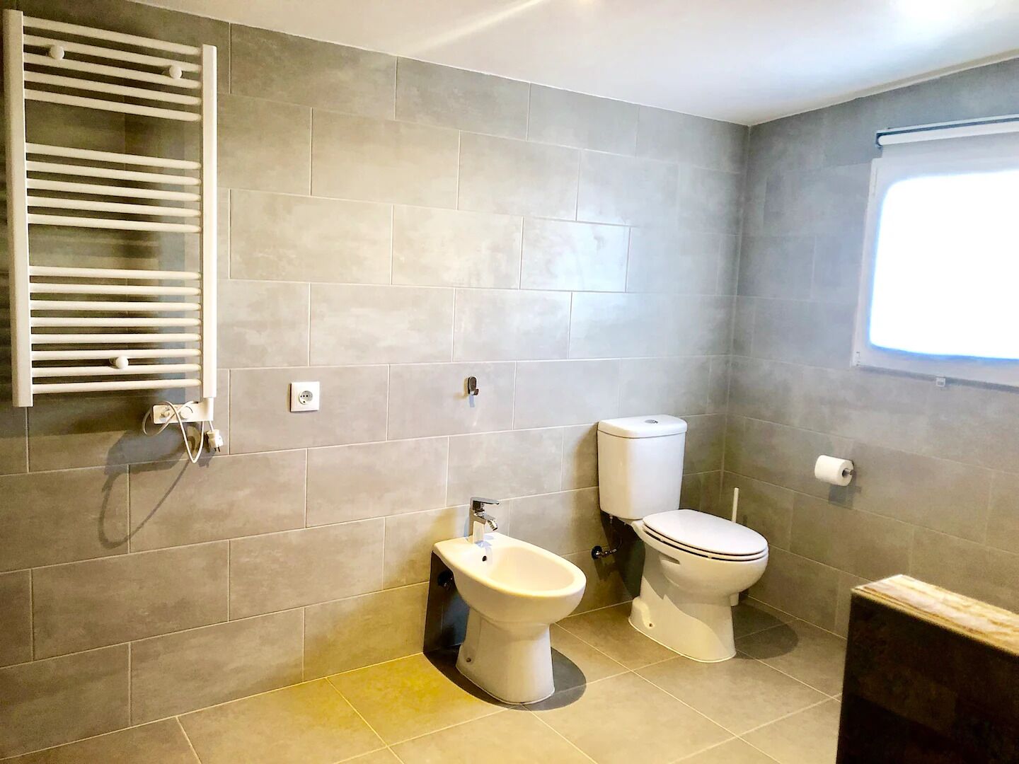 Une salle de bain équipée d’un bidet, de toilettes et d’un porte-serviettes.