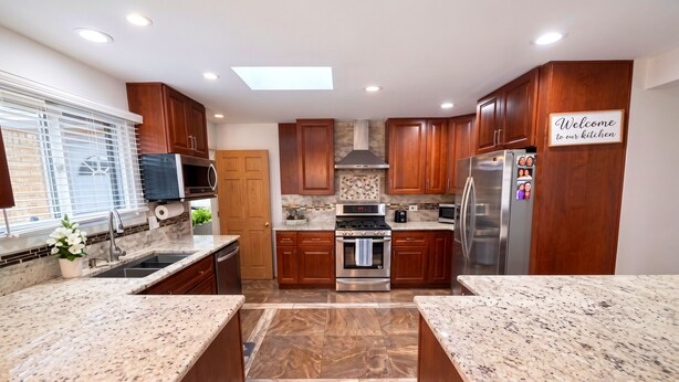 A modern kitchen with wooden cabinets, granite countertops, stainless steel appliances, and a 'Welcome to our kitchen' sign. - Amazing Mid-Term Rental Entire Home In Glenview (Northbrook)