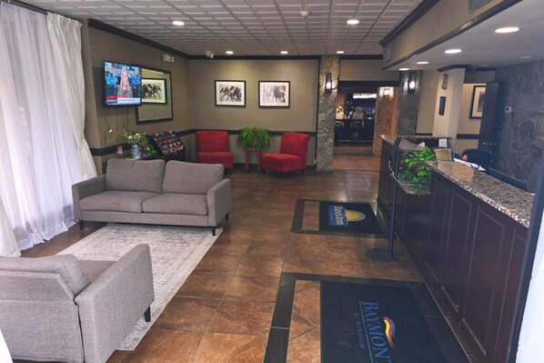 A lobby with a reception desk, red chairs, a grey sofa, and a TV mounted on the wall. - Days Inn By Wyndham Culpeper (Culpeper)