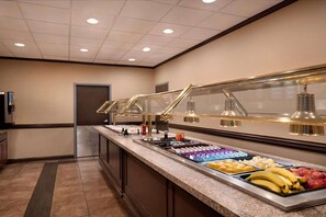 A buffet area with a variety of food items, including fruits and beverages, under glass display cases. - Days Inn By Wyndham Culpeper (Culpeper)