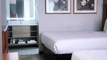 A hotel room with a bed, a desk, a mirror, and two framed pictures on the wall.