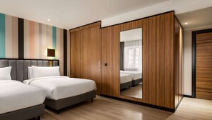 A modern hotel room with two beds, a large mirror, and a wardrobe with a wooden finish. - Ramada Encore By Wyndham Tashkent (Tashkent)