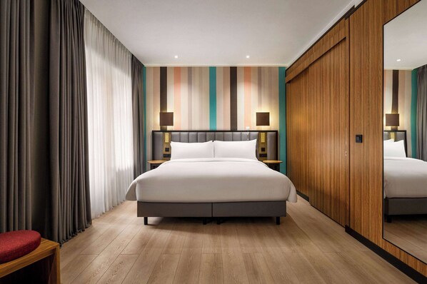 Una habitación de hotel moderna con una cama grande, un armario de madera y un espejo.