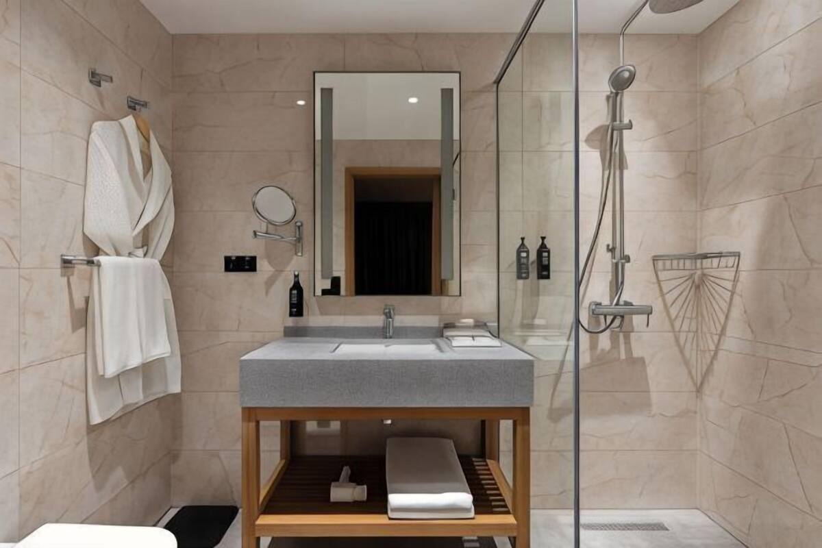 A modern bathroom with a glass shower enclosure, a wooden vanity with a sink, and a mirror.