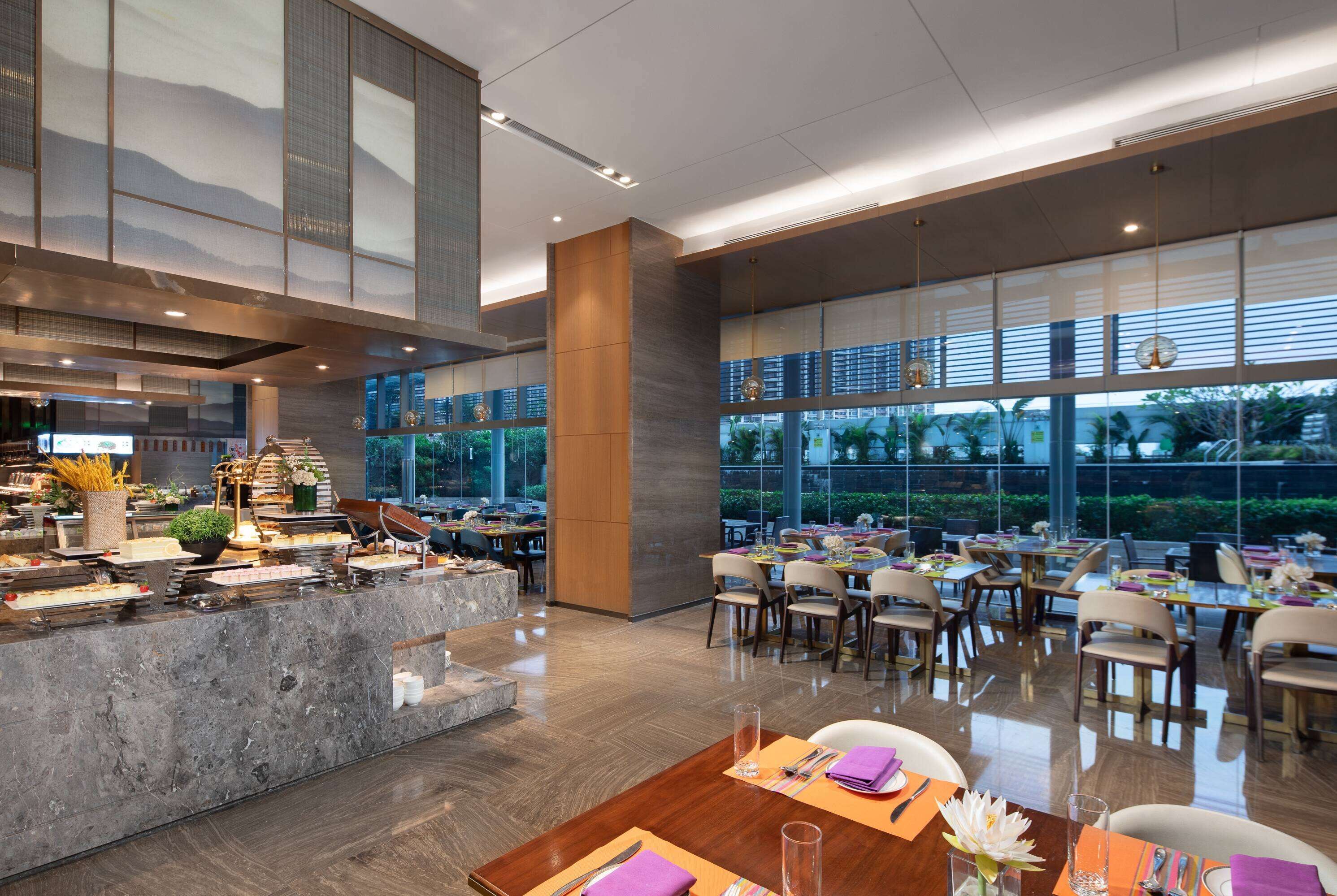 A modern restaurant with a central counter, dining tables, and chairs.