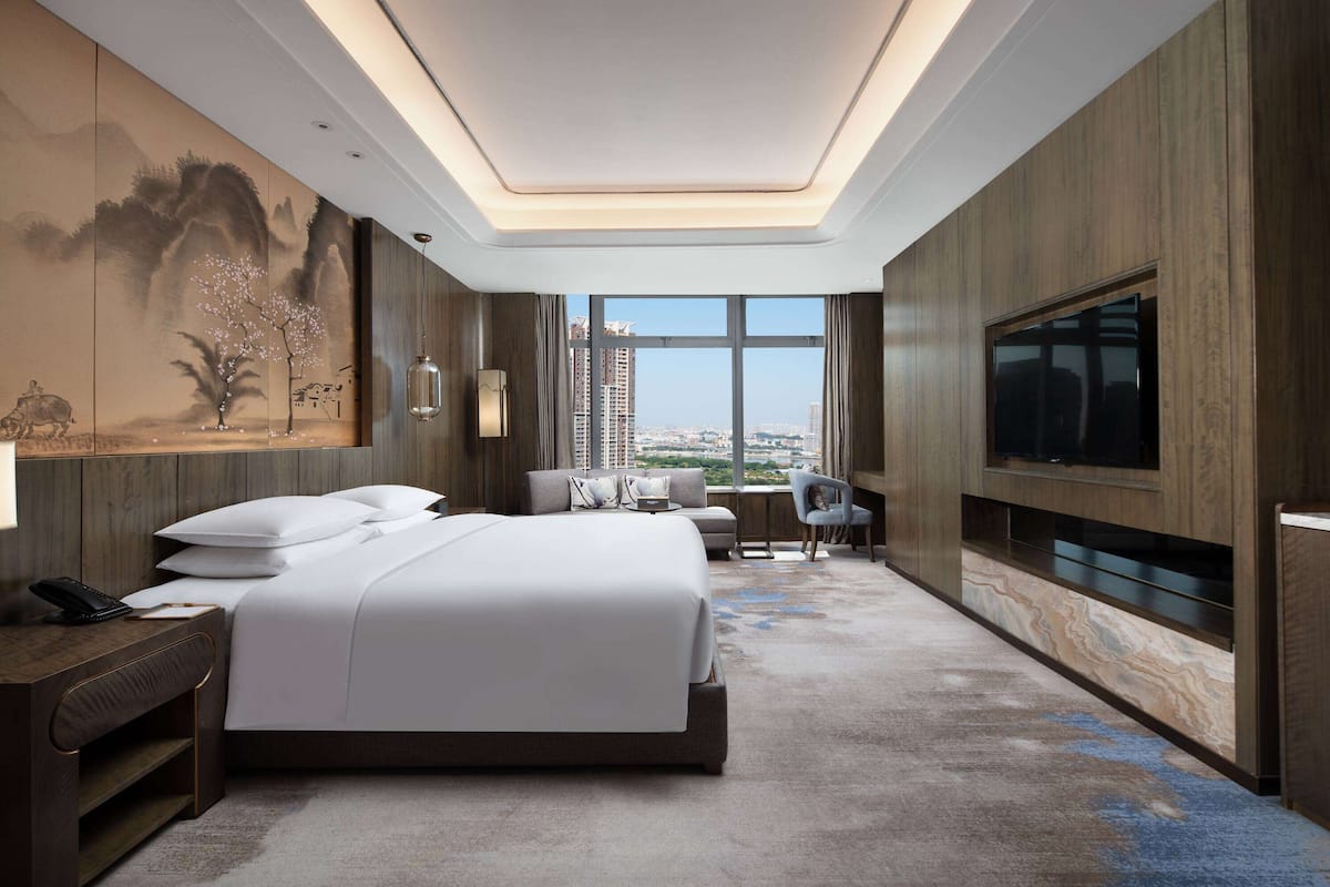 Habitación de hotel moderna con una cama grande, televisión, escritorio y vistas a la ciudad.