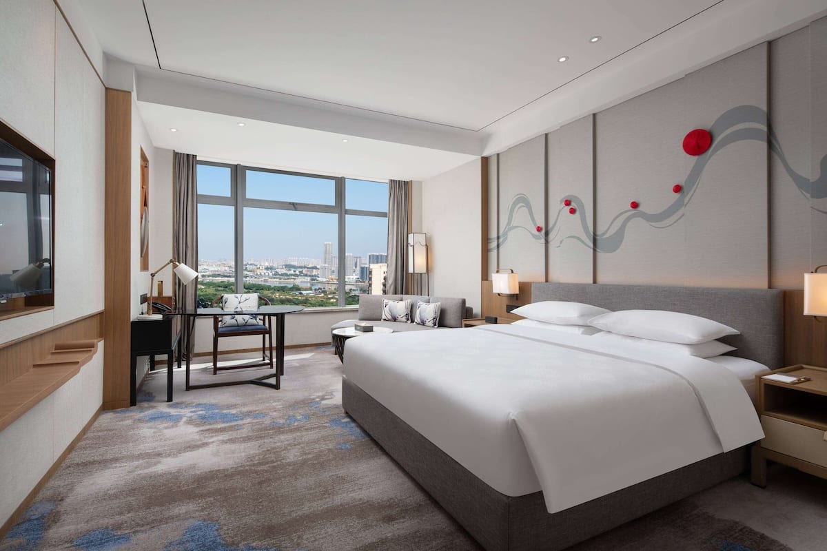 Habitación de hotel moderna con una cama grande, un escritorio y vistas a la ciudad.