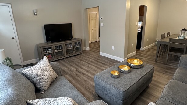 A modern living room with a ceiling fan, grey sofas, a TV, and a dining area in the background. - Minutes away from Presque Isle. 
On the ATV trail access and SNOWMOBILE Trail (Chapman)
