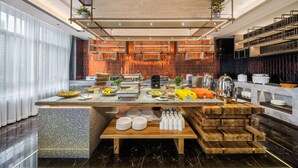 A modern hotel lobby with a buffet setup, marble flooring, and a decorative wall with vertical elements.