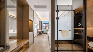A modern hotel room with a shower area, a bed, and a seating area with a table and chairs.