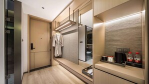 A modern hotel bathroom with a wooden vanity, a robe hanging on a rack, and toiletries on the counter.