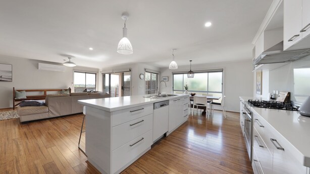 A modern kitchen with a central island, wooden flooring, and large windows. - Bayview Bliss in Surf Beach (Surf Beach)