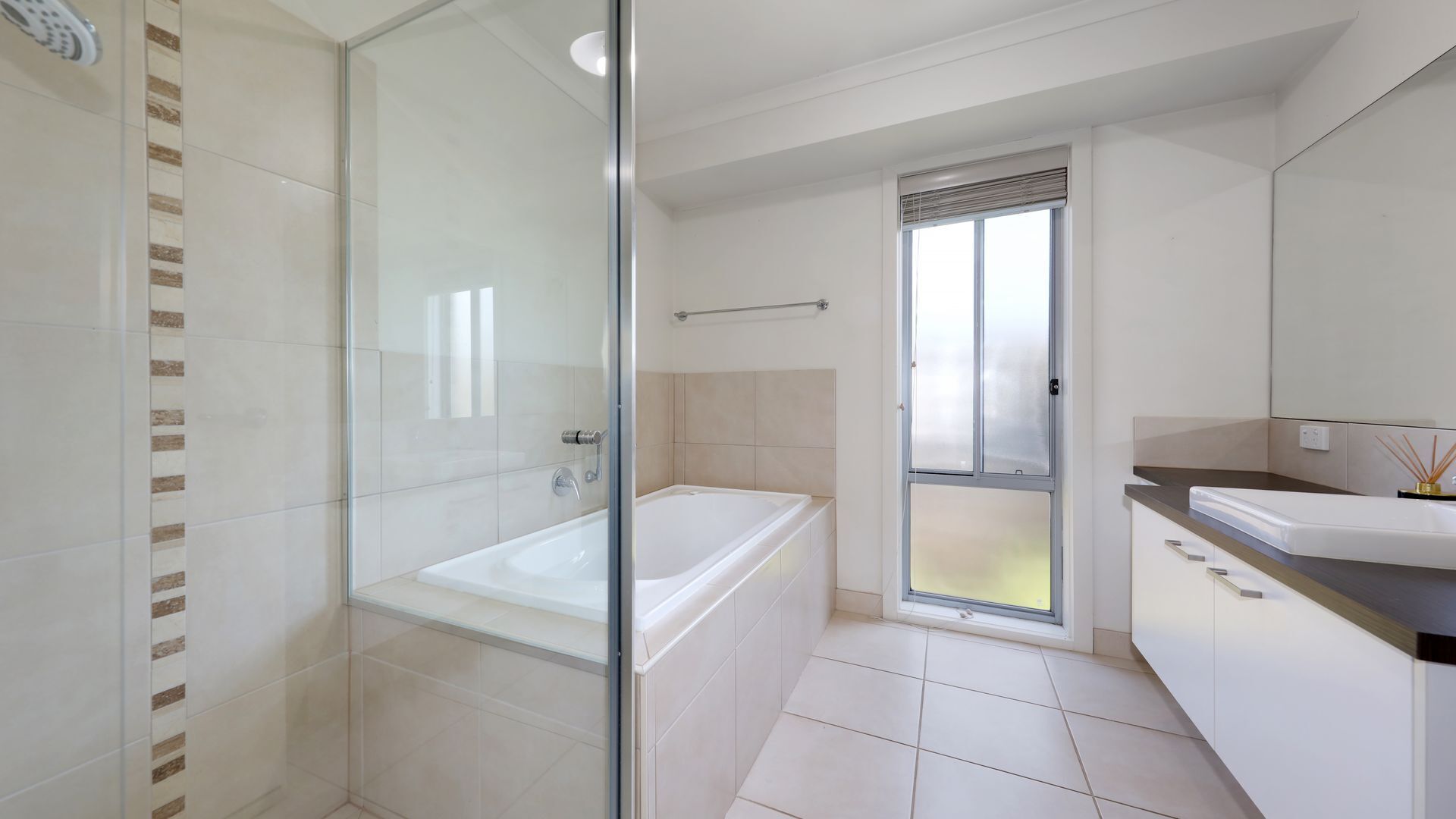 Een moderne badkamer met een douchecabine van glas, een vrijstaand bad en een wastafelmeubel met een wastafel en spiegel.