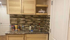 A kitchen with wooden cabinets, a tiled backsplash, and a granite countertop. - Lovely one bedroom unit  (Mississauga)