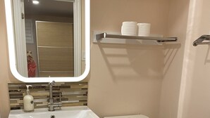 A bathroom with a white sink, dark-colored cabinet, toilet, and a mirror with a lighted frame. - Lovely one bedroom unit  (Mississauga)