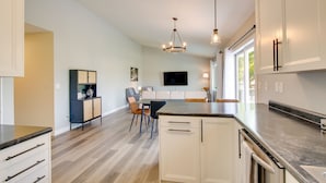 A modern kitchen with white cabinets, a granite countertop, and a built-in dishwasher. - Bright Little Chute Condo w/ Deck & Yard! (Little Chute)