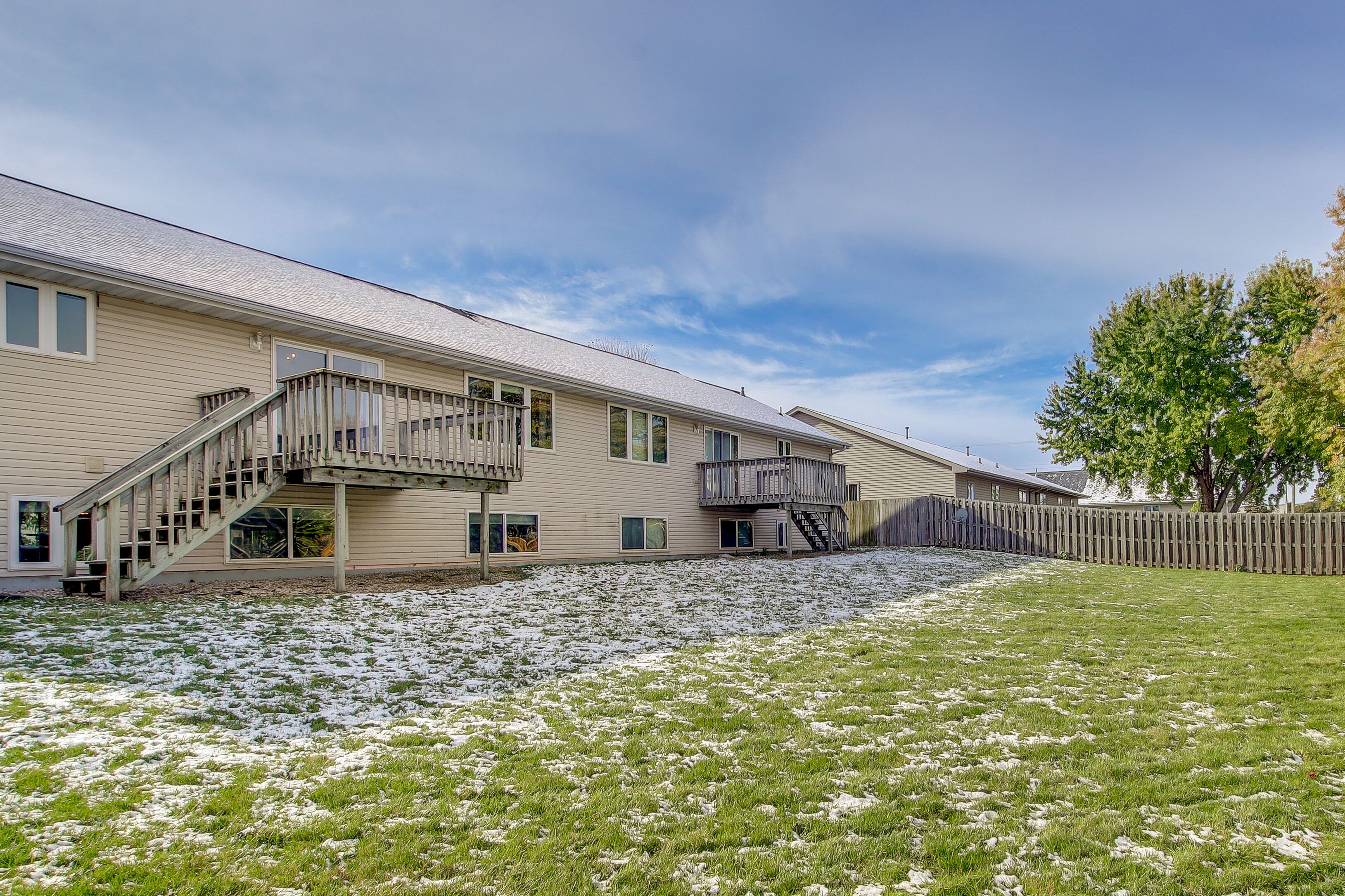 A two-story building with a covered outdoor area, a staircase, and a fenced yard.