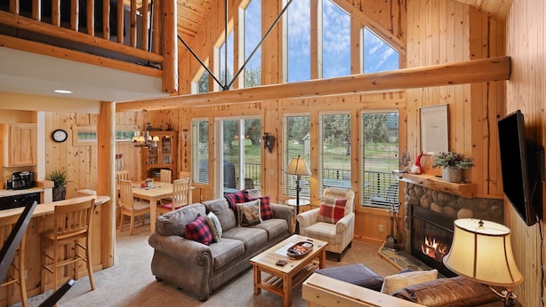 Un intérieur de chalet en bois spacieux, comprenant un coin repas, un salon et une cheminée.