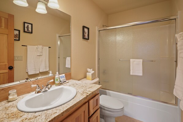A bathroom with a sink, mirror, toilet, and glass-enclosed shower.