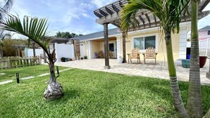 A well-maintained lawn with a palm tree and a decorative planter. - NEW! Stylish & Cozy Sea Grape near Beach & Flagler (New Smyrna Beach)