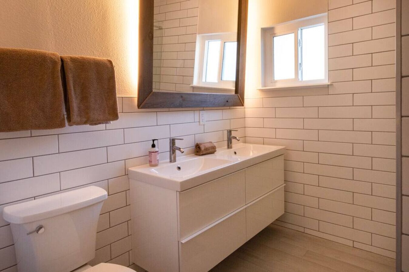 Een badkamer met een wit toilet, een wastafel met een spiegel erboven en een handdoek aan de muur.