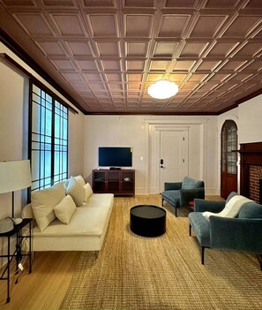 Un salon comprenant un canapé, deux fauteuils, une table basse, un téléviseur et une cheminée.