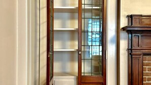 Un passadís estret amb una porta de fusta que dona a una habitació amb prestatgeries integrades i una llar de foc.