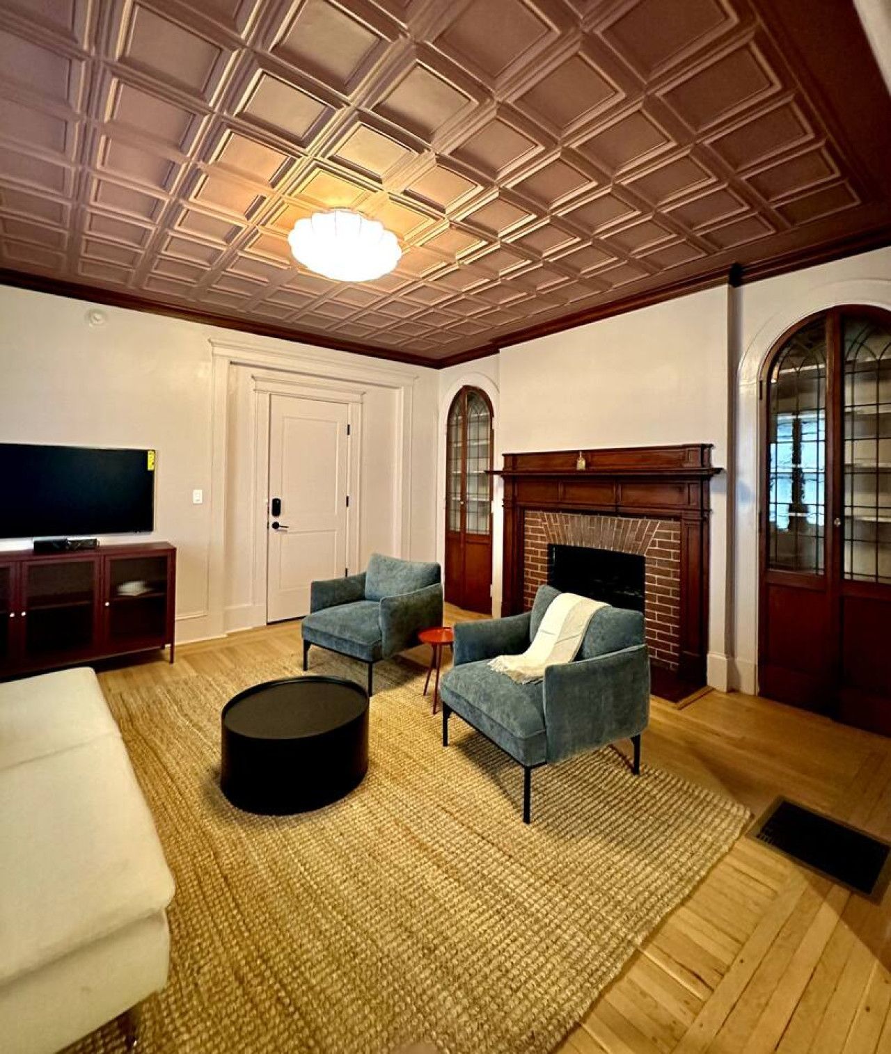 A living room with a fireplace, two armchairs, a round coffee table, and a television on a stand.