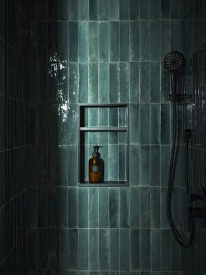 A bathroom with a shower, a bottle of shampoo in a shelf, and a towel rack. - Elm Grove Co.Housenhv (Downtown New Haven)