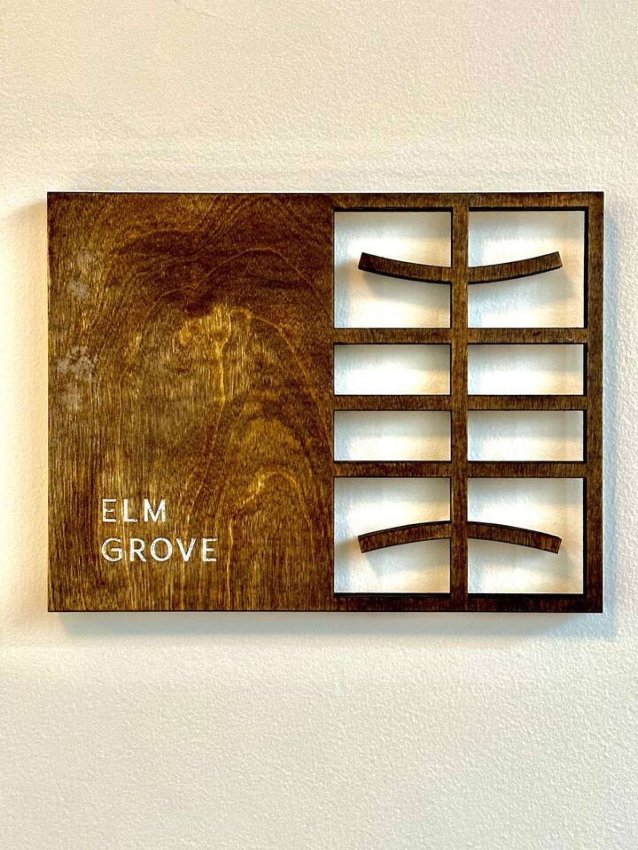 A wall-mounted light fixture with a wooden design and the text "ELM GROVE".