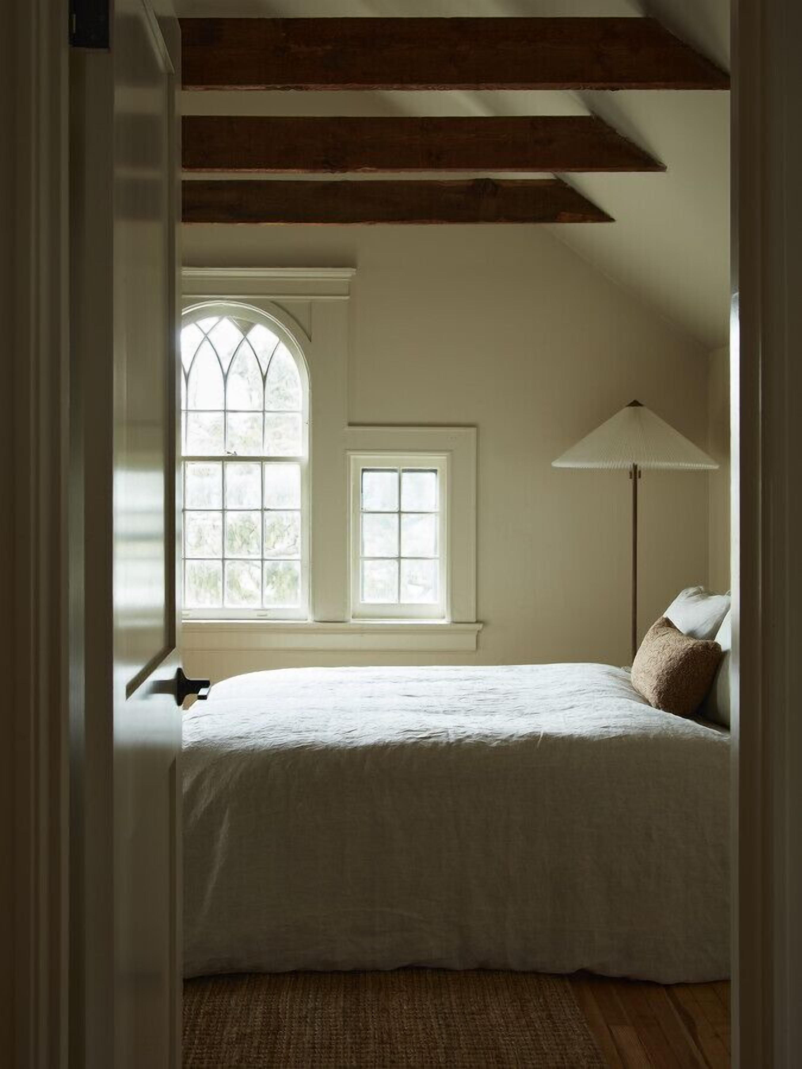 Ein Schlafzimmer mit einem großen Bett, einem Fenster und einer Stehlampe.