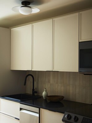 A kitchen with white cabinets, a black countertop, a sink, and a stove.