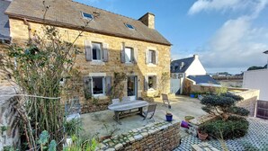 A stone house with a tiled patio, outdoor seating, and a garden area.