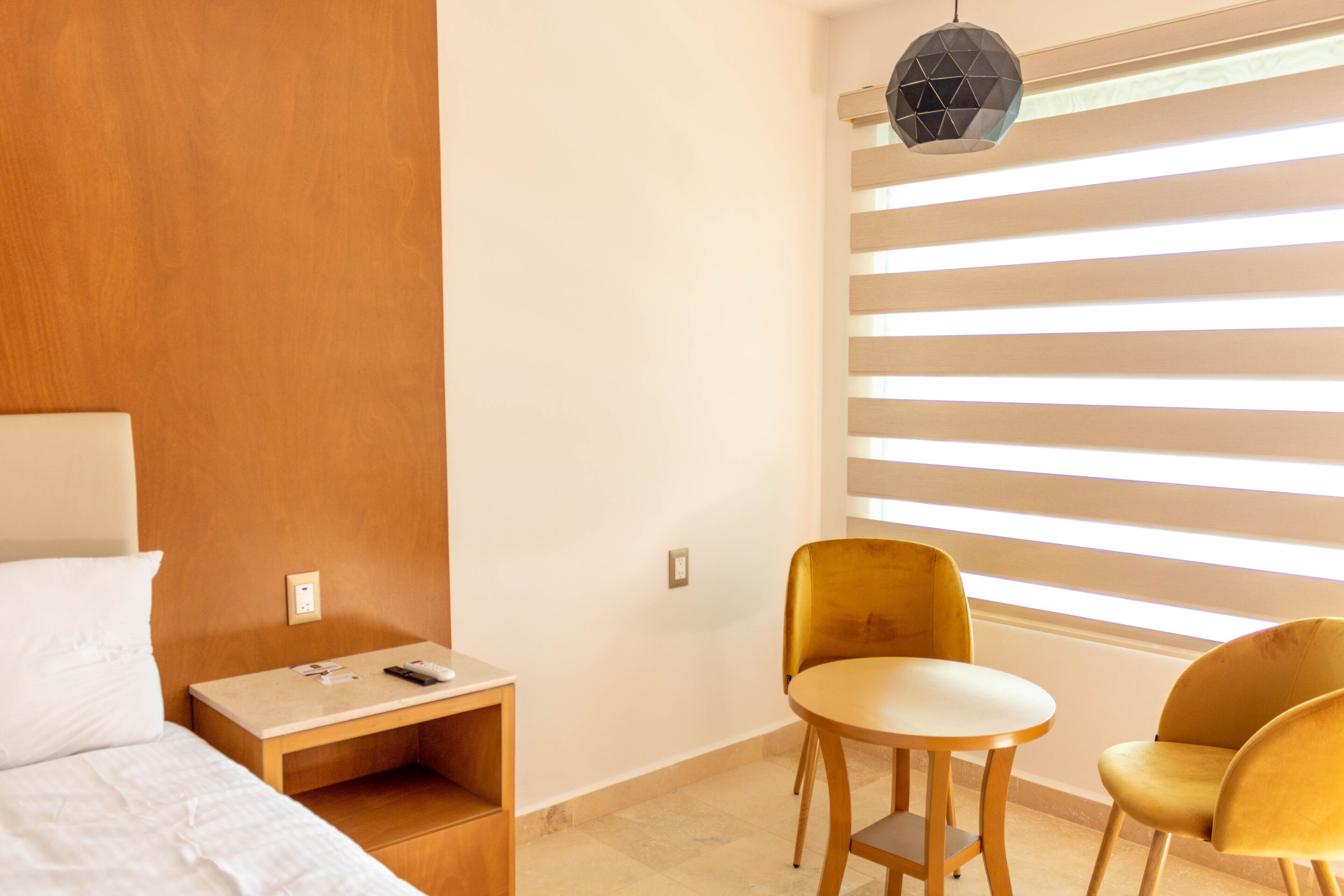 A hotel room with a bed, bedside table, and a seating area with two chairs and a small table.