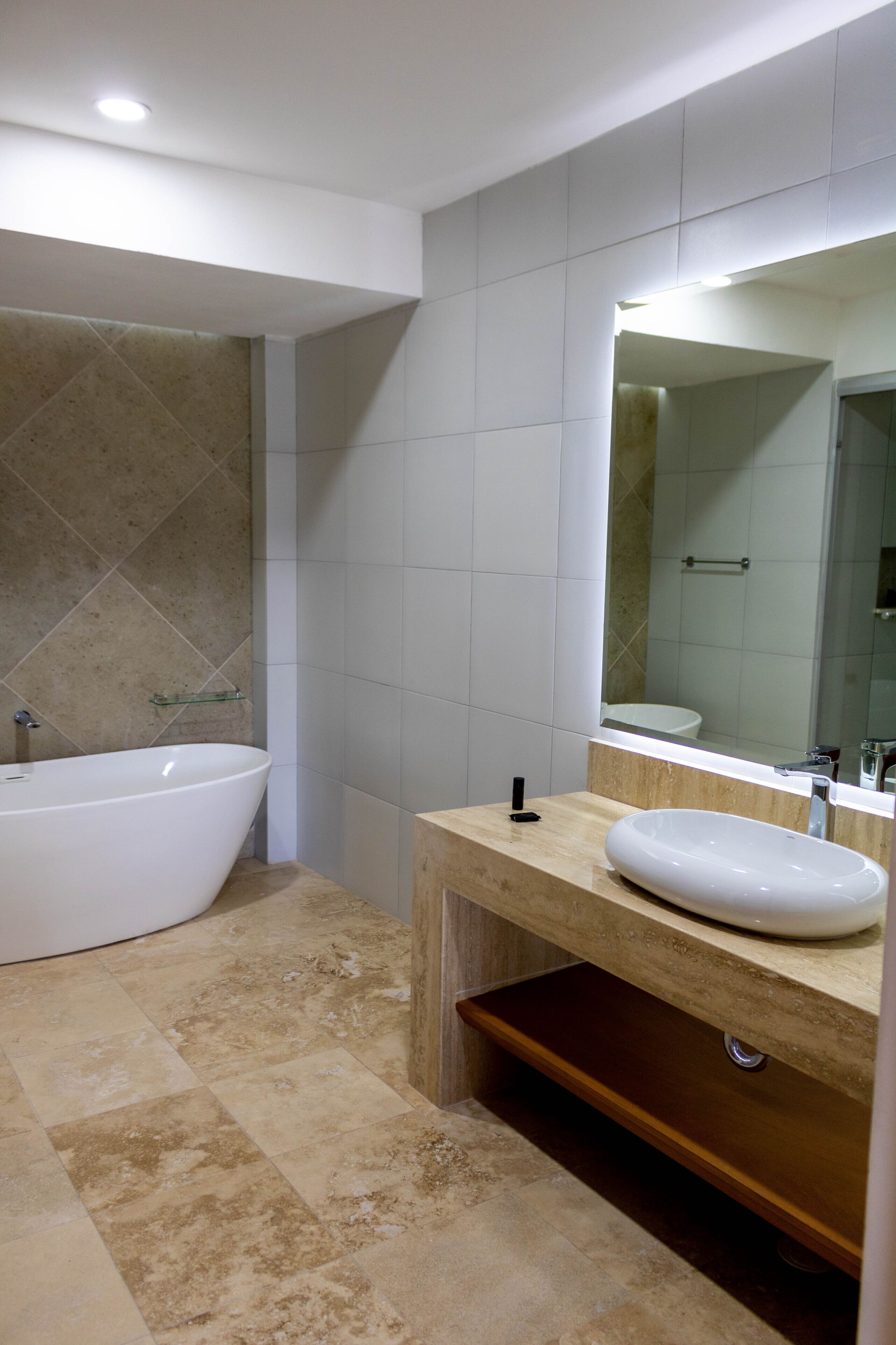 Un bagno moderno con una vasca freestanding, uno specchio grande e un mobile bagno in legno con lavello.