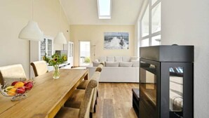 Una sala de estar moderna con una mesa de comedor de madera, un sofá y una chimenea.