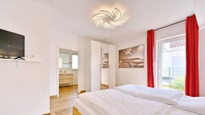 Un dormitorio moderno con una cama de madera, un televisor de pantalla plana y una lámpara en el techo.