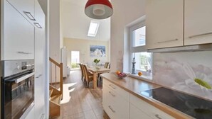 Una cocina moderna con armarios blancos, encimera de madera y un amplio ventanal.