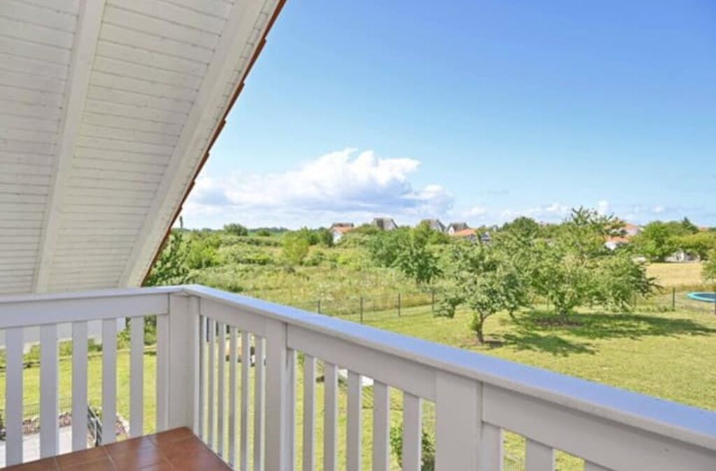 Ein Balkon mit Blick auf eine grüne Landschaft und Häuser in der Ferne.