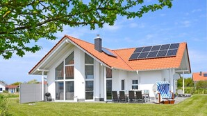A modern house with a red roof, large windows, and a solar panel on the roof. - Villa Meereszeit (Trent)