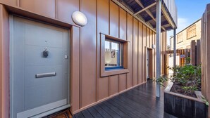A modern building with a grey door, a small window, and a wooden deck. - SERCASA - Appletree Court - Kingston (Kingston Upon Thames)