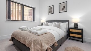 A bedroom with a bed, a nightstand, a window, and two framed artworks. - SERCASA - Appletree Court - Kingston (Kingston Upon Thames)