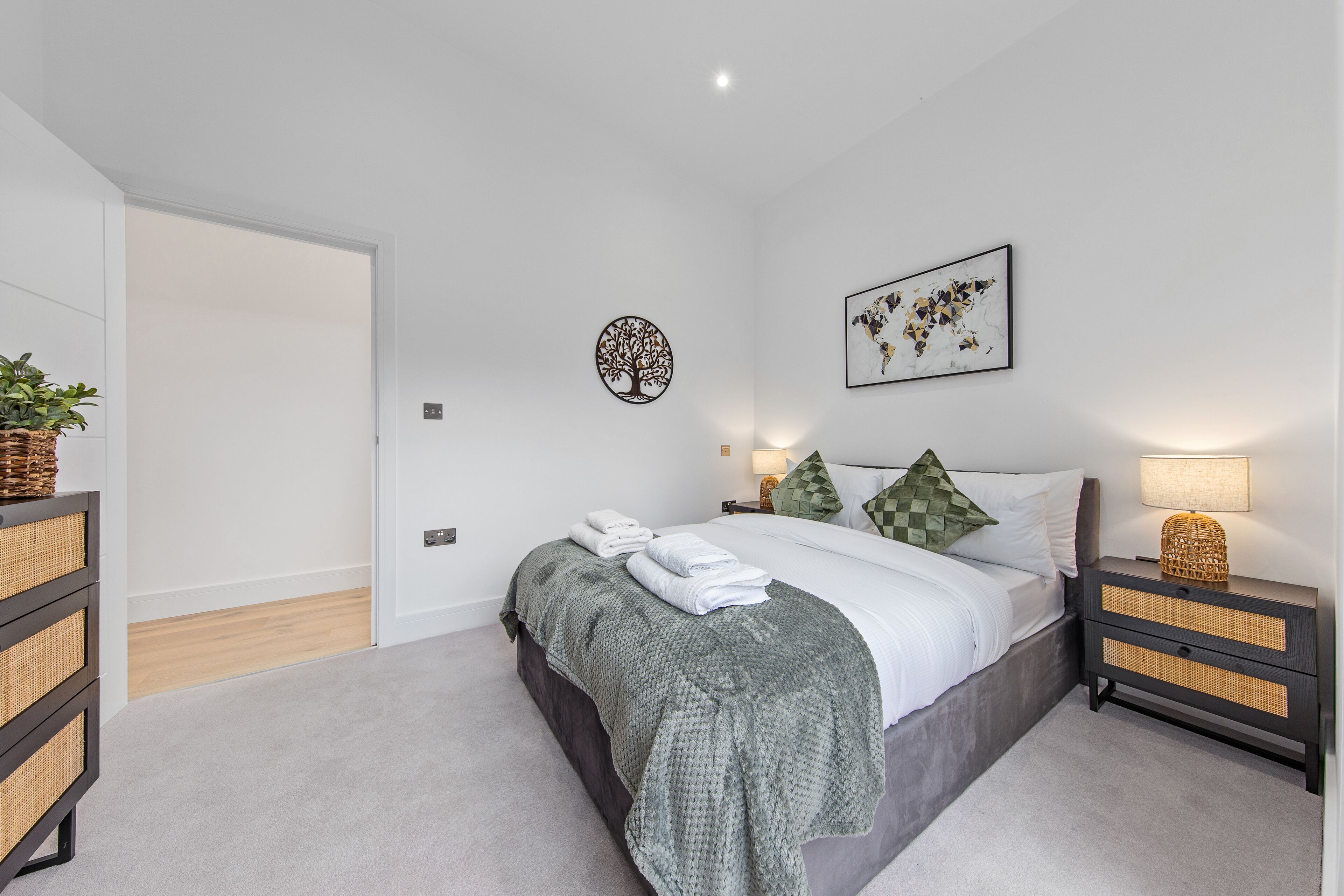 A bedroom with a bed, bedside tables, a lamp, a wall art piece, and a door.