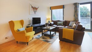 A modern living room with a sofa, armchair, coffee table, and television. - Fabulous 3 bedroom property in city centre location. Sleeps 5. (Edinburgh)