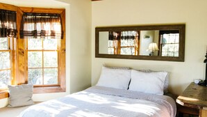 A bedroom with a large bed, wooden ceiling, and a window with curtains. - Sagewood Cabin @ Whispering Oaks, 20 miles from Moab! (Moab)