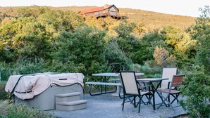 An outdoor patio with a covered seating area, a table, and chairs. - Grey Dawn Cabin @ Whispering Oaks, 20 miles from Moab! (Moab)