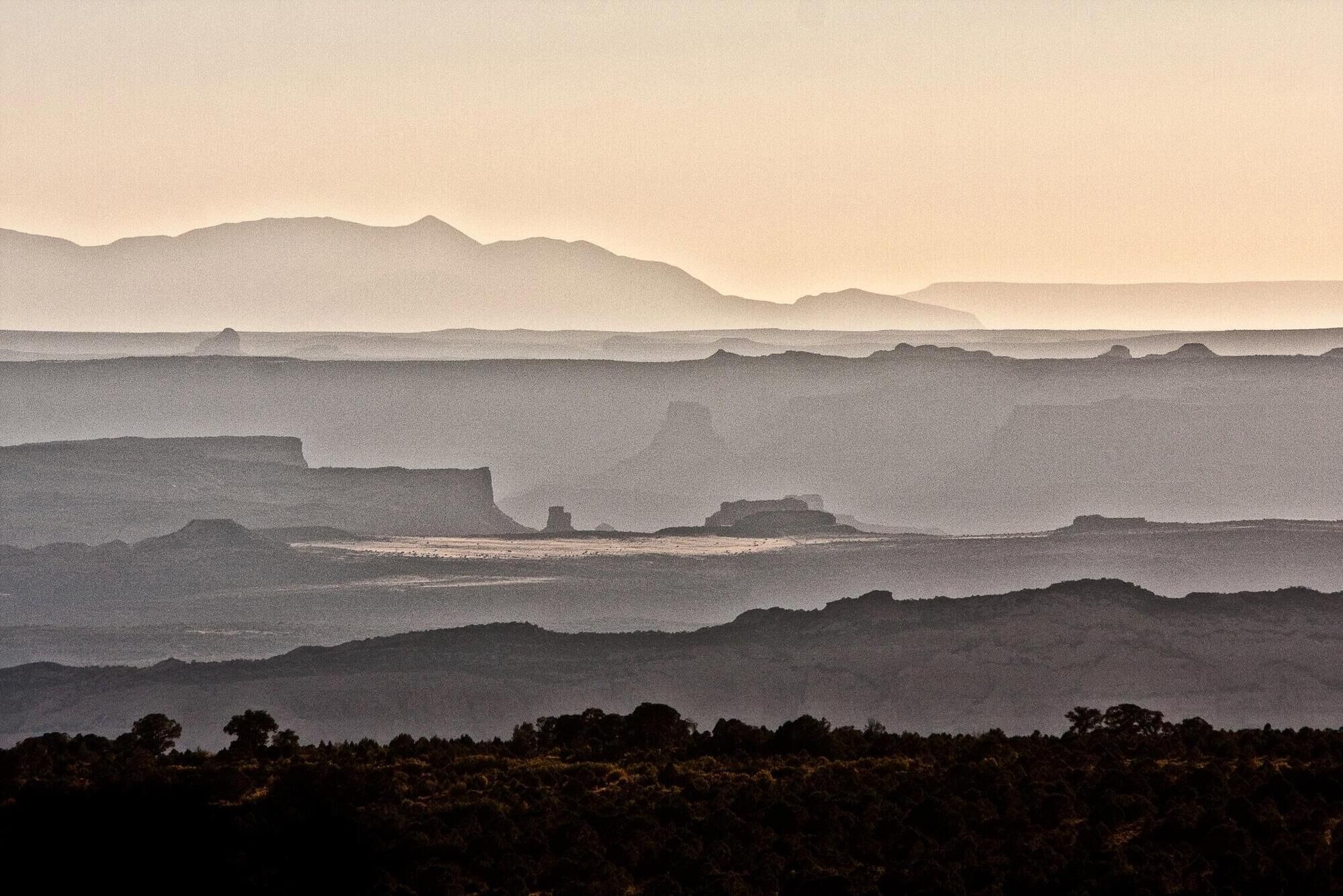Un paysage côtier caractérisé par des collines en terrasses et une chaîne de montagnes lointaine.