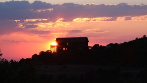 A house silhouetted against a sunset with a clear sky.