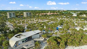 A modern hotel with a rooftop pool, surrounded by palm trees and a beach. - Simply step across the street from this condo to reach Florida's premier beach! (Siesta Key)